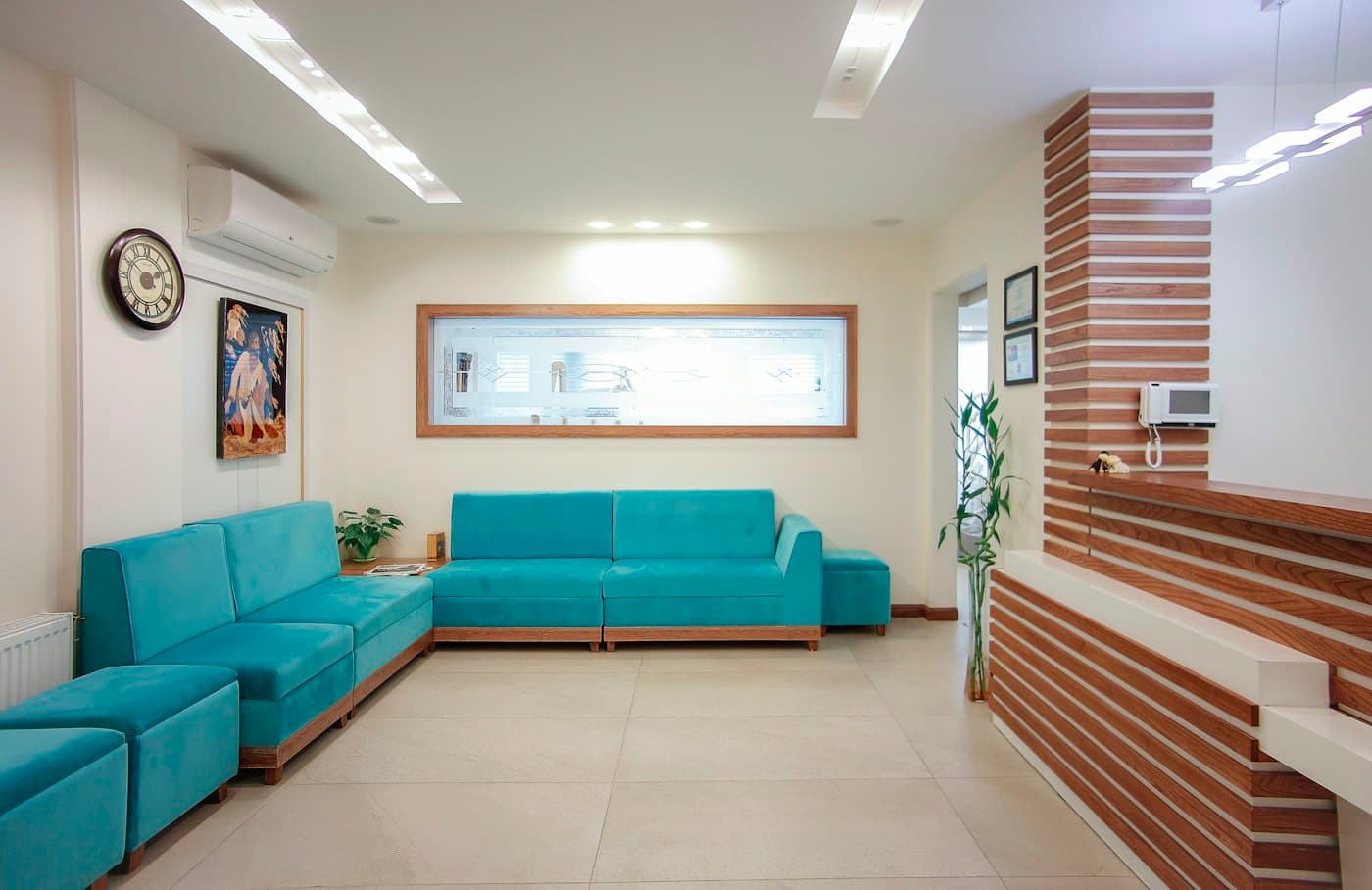 Phòng chờ có sofa xanh, cây xanh và quầy lễ tân ốp gỗ